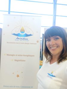 Sandrine devant le logo de son activité Massages Âm'ondina